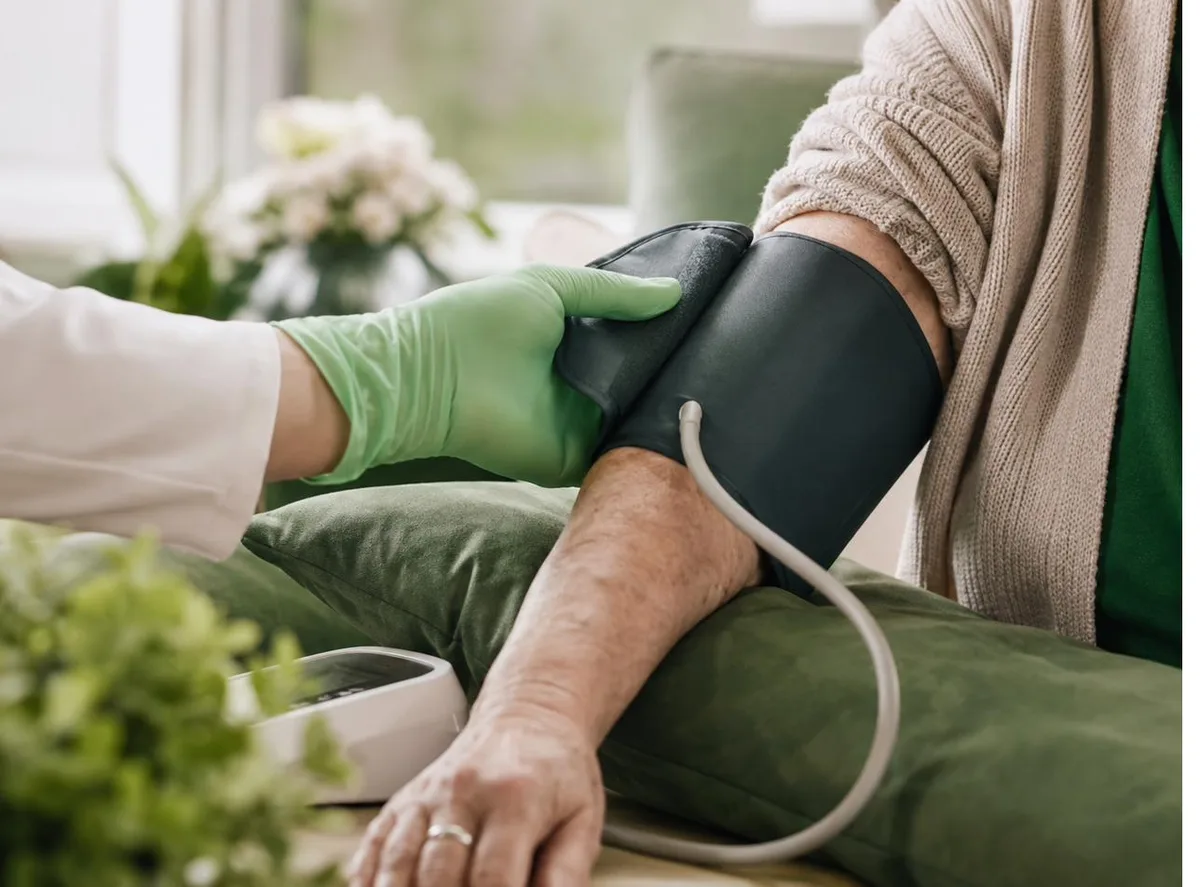 Pharmacist checking blood pressure on an older adult patient at home